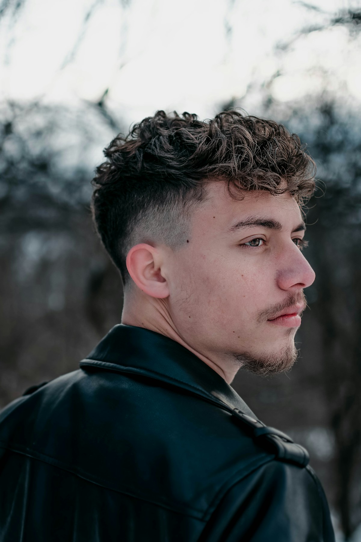 Cheveux bouclés gardés sur le dessus, côtés dégradés