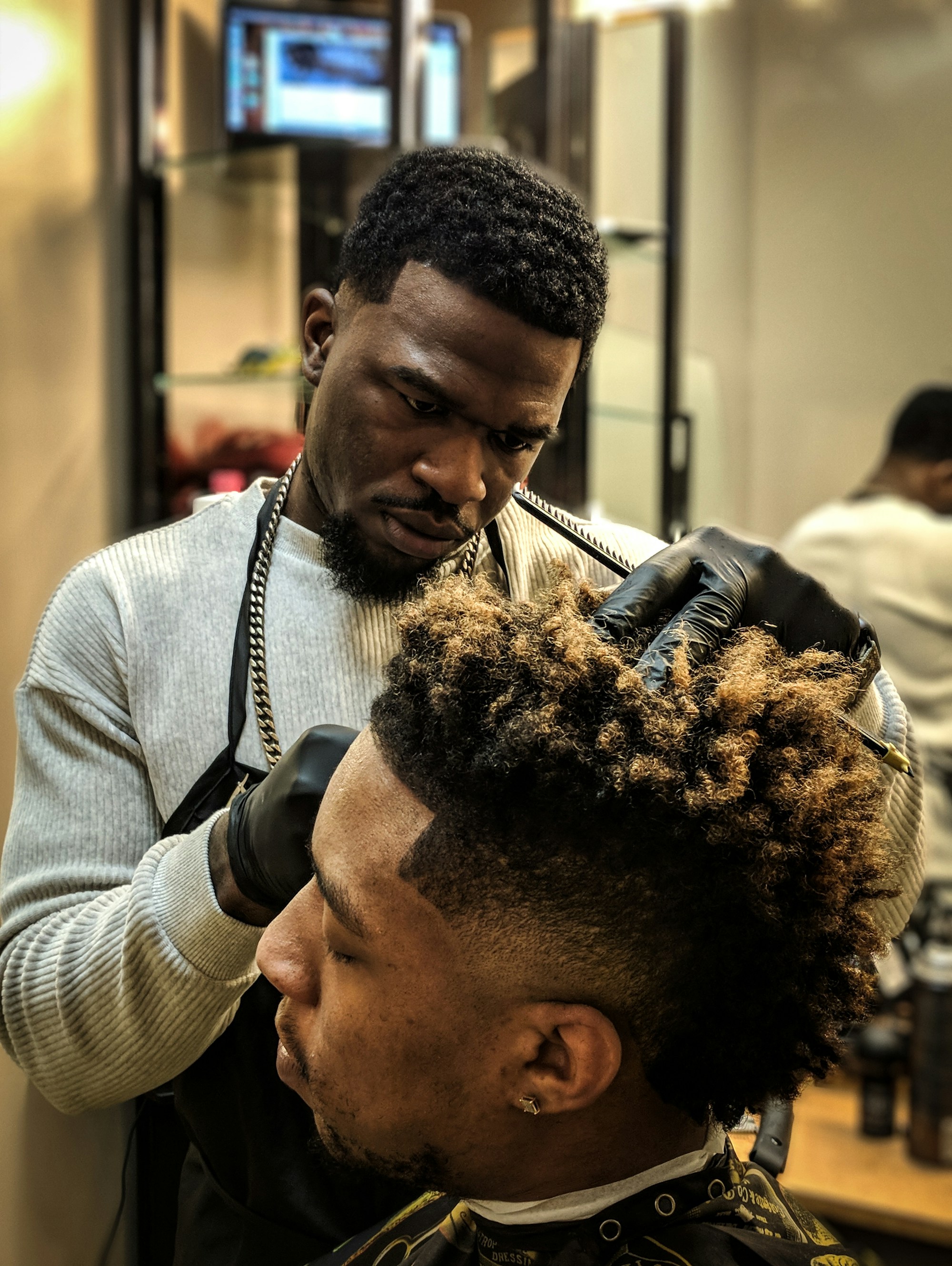 Un barber réalise un dégradé sur un client aux cheveux bouclés