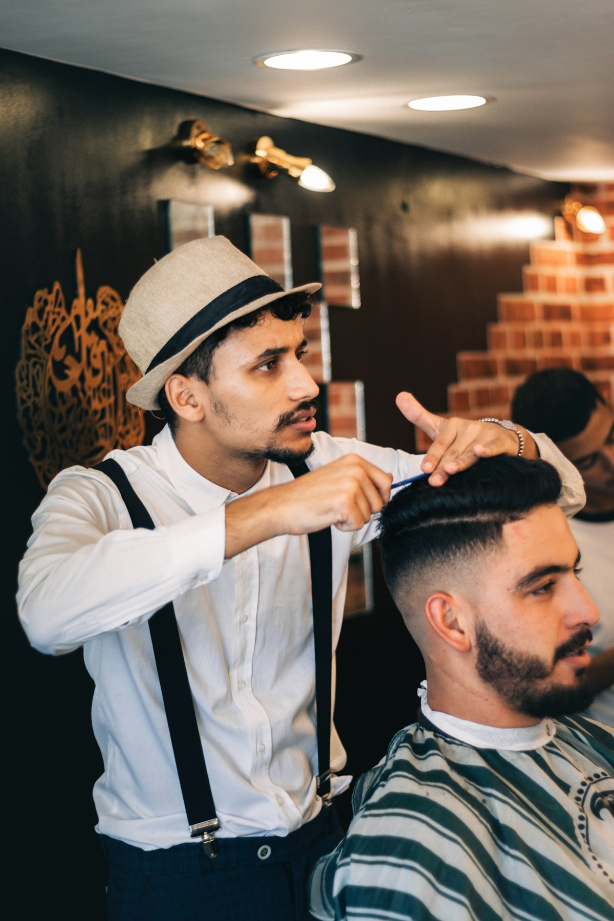 Un barbier en chapeau taille la barbe d'un client