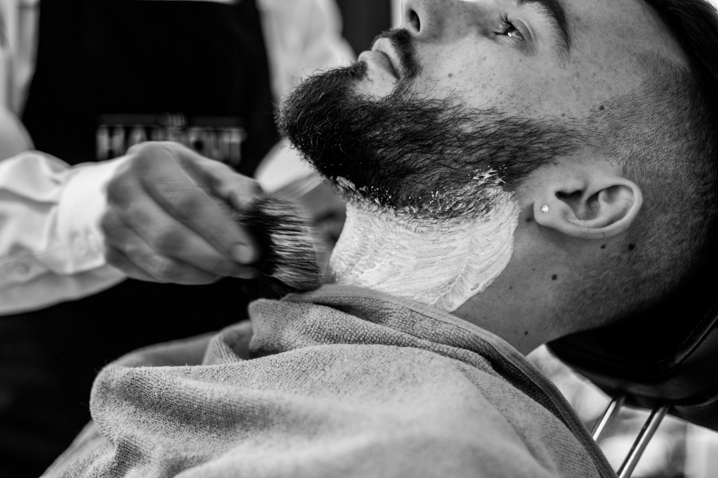 Rasage au coupe-chou sur une barbe couverte de mousse, en noir et blanc