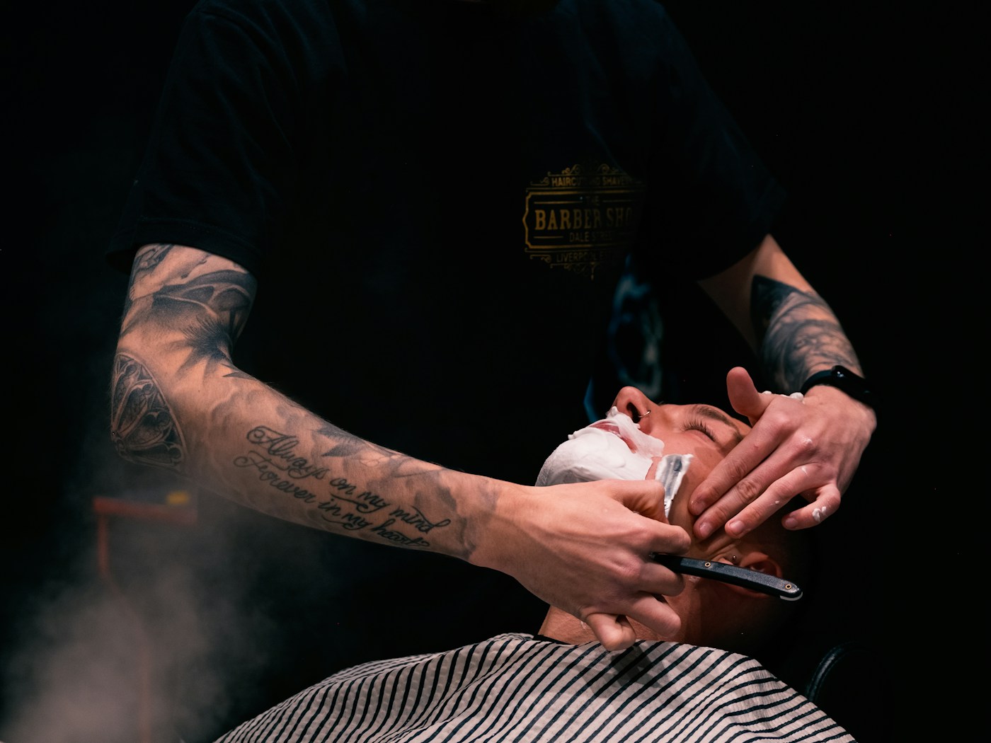 Un barbier prépare le rasage d'un client allongé